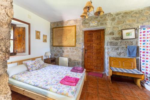 a bedroom with a bed and a stone wall at Isla Del Burguillo in Ávila