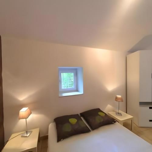 a bedroom with a bed and two tables and a window at Gîtes du Parc in Vallon-Pont-dʼArc