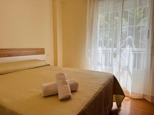 a bed with a towel on it with a window at Comodidad cerca del centro Granada in Albolote