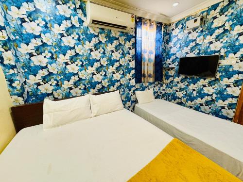 two beds in a room with a wall covered in flowers at MSN-Gate1Temple in Srikalahasti