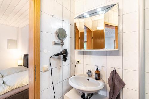 a bathroom with a sink and a mirror and a bed at Haus Ersfeld – Gartenstudio in Bad Teinach-Zavelstein