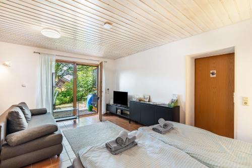 a bedroom with a bed and a couch and a television at Haus Ersfeld – Gartenstudio in Bad Teinach-Zavelstein