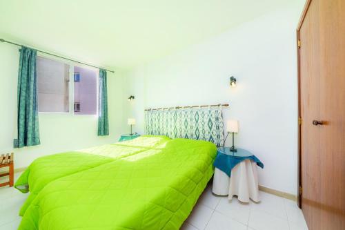 a bedroom with a green bed and two tables at Apartamento Grillo in Cala Ratjada