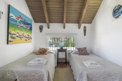 two beds in a room with white walls and wooden ceilings at El Rincon del Che in Zahora