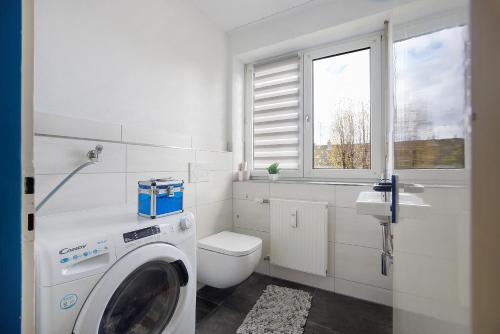 a white bathroom with a washing machine and a toilet at Allgäu Space in Marktoberdorf
