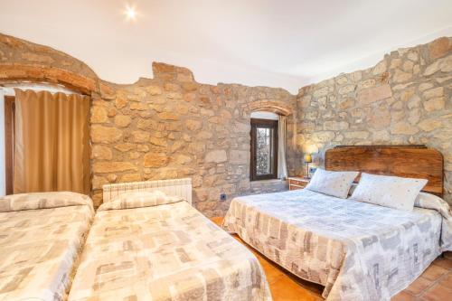 a bedroom with two beds and a stone wall at El Puig De Fonollet in Puigreig