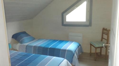 a bedroom with two beds and a chair and a window at Les Hirondelles du Cap in Plévenon