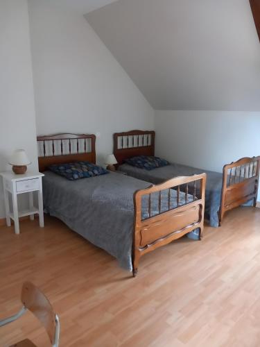 a bedroom with two beds and a table and a chair at Gîte Le Guerichet in Betton