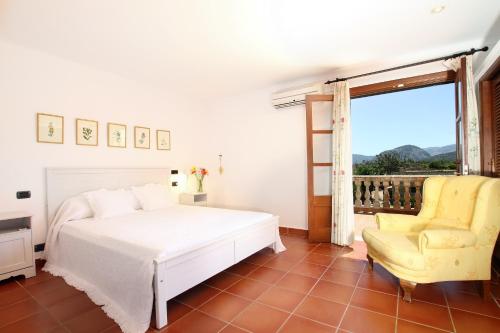 a bedroom with a bed and a chair and a window at Can Seguinot in Pollença