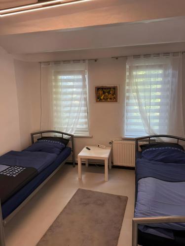 two beds in a room with windows and a table at Monteurswohnung Rothentor4 in Dorf Mecklenburg