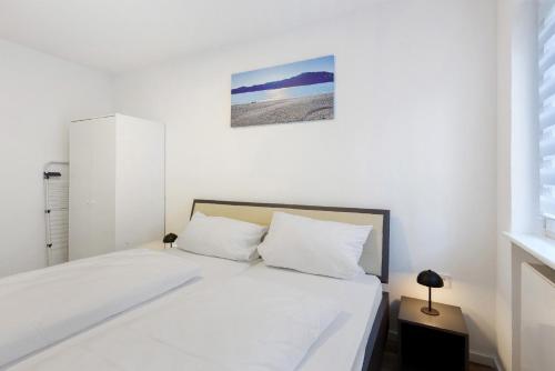 a white bedroom with a bed with white sheets at Fewo am Mühlenbach in Wehr
