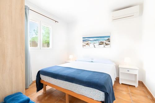 a white bedroom with a bed with a blue blanket at Las Estrellas Cala Llombards in Cala Llombards