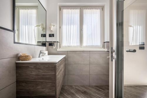 a bathroom with a sink and a mirror and a shower at Appartamenti Gaggiolo 1 in Dro