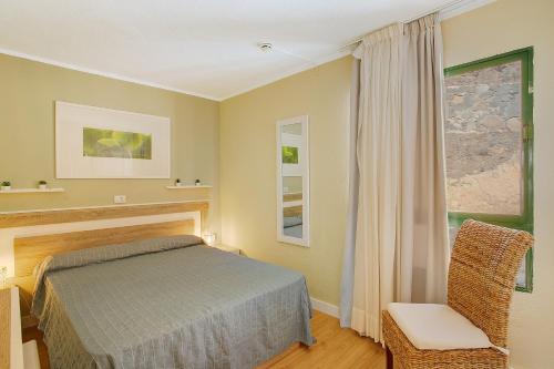a bedroom with a bed and a chair and a window at Zen House in Puerto Rico de Gran Canaria