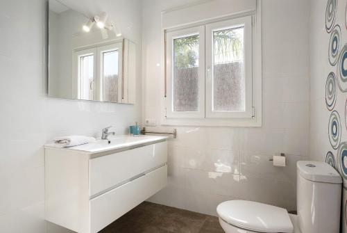 a white bathroom with a toilet and a sink at Villa Montenmedio - Carmelo in El Soto