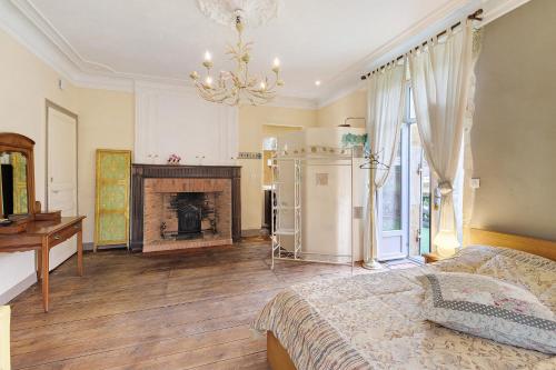 a bedroom with a fireplace and a bed and a chandelier at La Belle Gabarre in Groléjac