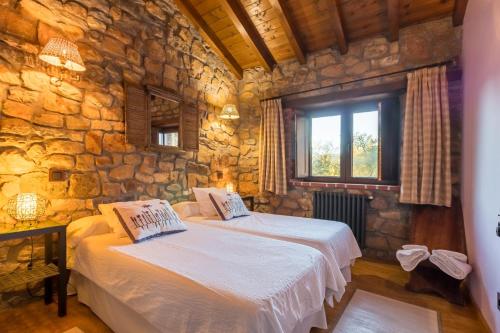 a bedroom with two beds in a stone wall at El Paraiso del Yayo in Ramales de la Victoria