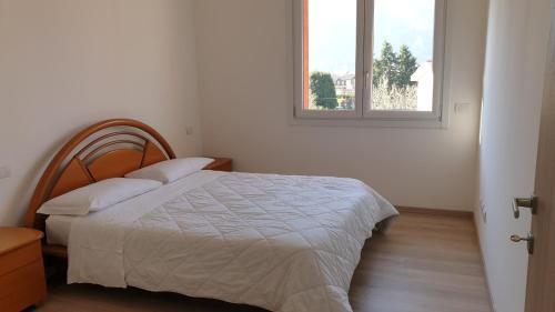 a white bedroom with a bed and a window at Modern apartament in Porlezza