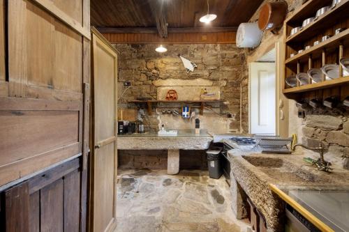 a kitchen with a sink and a stone wall at Casa Do Riacho - Douro in Armamar