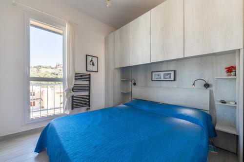 a bedroom with a blue bed and a window at Gemma Piccolino in Villasimius
