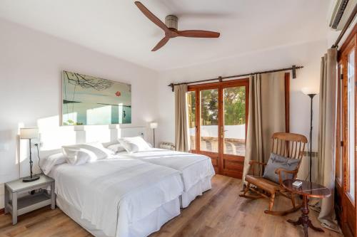 a white bedroom with a bed and a chair at Bon Viure in Marratxí 