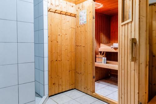 a bathroom with a shower with a wooden wall at Haus Seeblick in Langballig