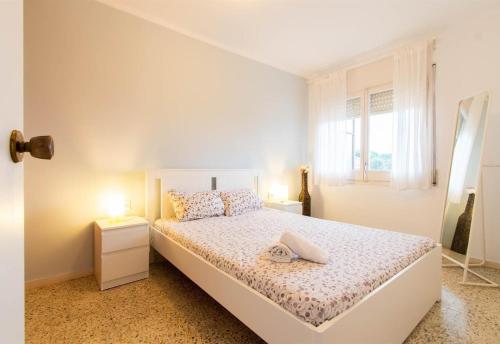 a white bedroom with a bed and two lamps at Moli Apartment Beach in Canet de Mar