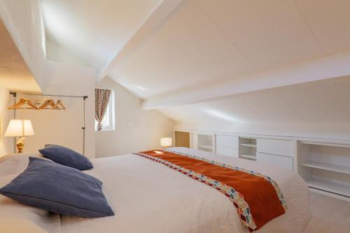 a bedroom with a large white bed with blue pillows at Le Barry in Tulette