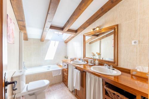 a bathroom with two sinks and a mirror and a tub at Casa el Arroyal in Rades de Abajo