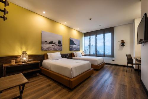 a bedroom with two beds and a table and a desk at Diez Hotel Categoría Colombia in Medellín