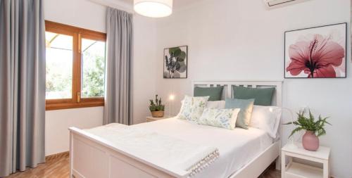a white bedroom with a large bed and a window at Villa Hort de Can Rafalet in Ses Salines