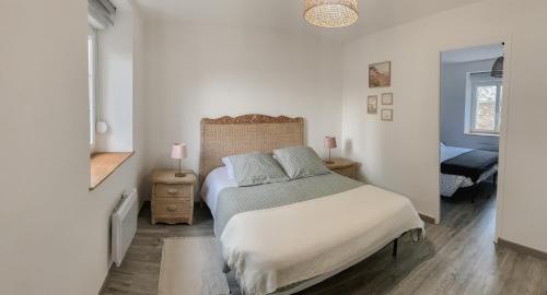 a white bedroom with a bed and a window at Gîte bord de mer - le Chardon in Pirou