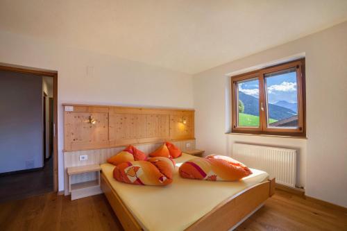 a bedroom with a bed with orange pillows and a window at Fichtenhof Wohnung Edelweiss in Tarces