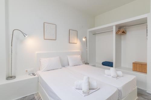a white bedroom with a large white bed with two towels at A Tinian Room 2 in Tinos