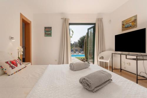 a bedroom with a white bed with a flat screen tv at El refugio in La Oliva