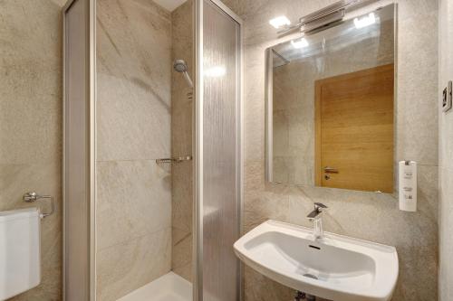 a bathroom with a sink and a shower with a mirror at Premium App Hofer Barbara in Villabassa