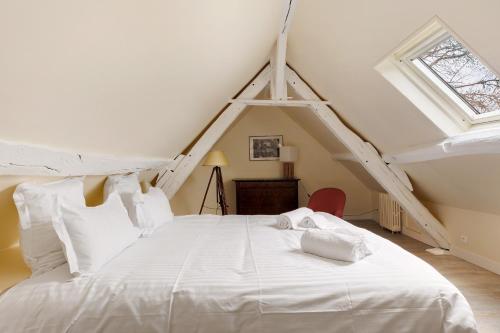 a bedroom with a white bed in a attic at La Petite Trigalière in Ambillou
