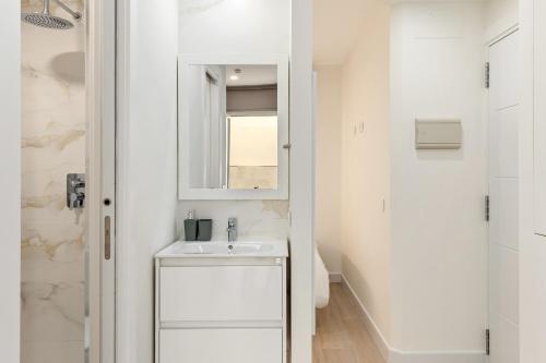a white bathroom with a sink and a mirror at Cala Azul-few steps from the beach in La Cala de Mijas