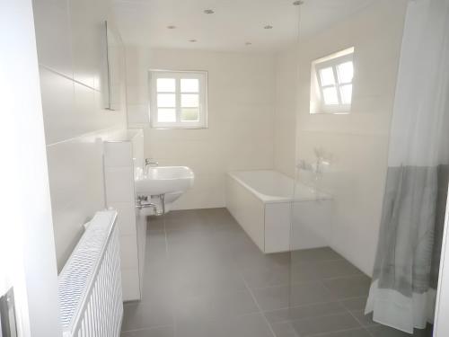 a white bathroom with a sink and a bath tub at Ferienhaus Drelsdorfer Forst in Drelsdorf