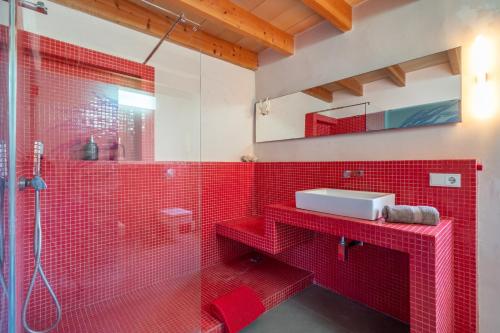 a red bathroom with a sink and a shower at Casa Sorteta, en el centro de Artà in Artá
