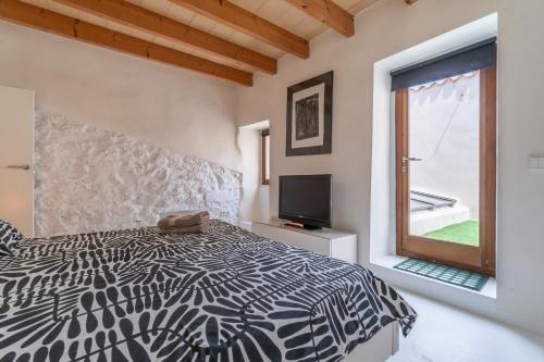 a bedroom with a black and white bed and a window at Casa Sorteta, en el centro de Artà in Artá