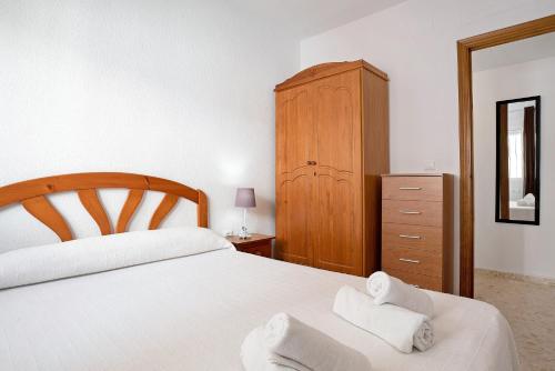 a bedroom with a white bed and a wooden cabinet at Sagasta 1 - Andalmar in Conil de la Frontera