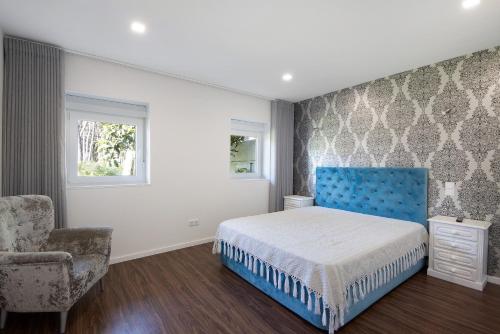 a bedroom with a blue bed and a chair at Moradia Pinheiro Manso in Apúlia