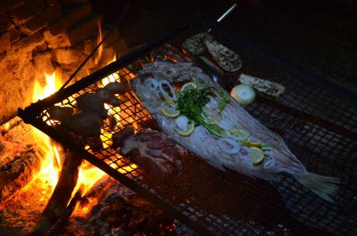 a fish on a grill next to a fire at La Brújula Hostel in La Paloma