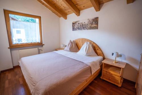 a bedroom with a large white bed and a window at Appartamento Bucaneve in Predazzo