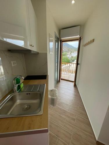 a kitchen with a sink and a door to a balcony at Lissos Rooms Sougia in Sougia