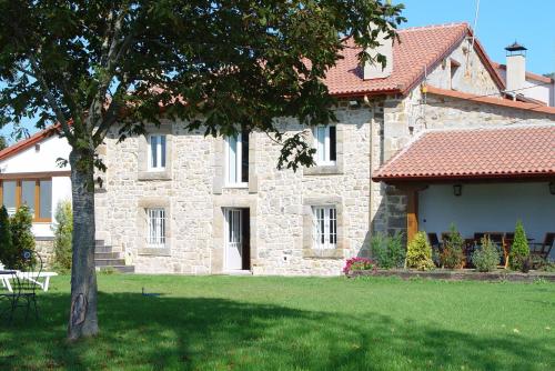 a stone house with a tree in front of it at Casa del Lago de Campoo in Orzales