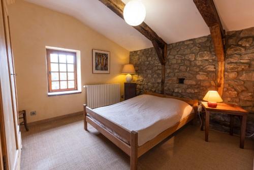 a bedroom with a bed and a stone wall at Les Grisiéres in Montpezat-sous-Bauzon