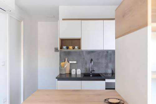 a kitchen with white cabinets and a sink at Barrosu Studio Apartment in Orosei