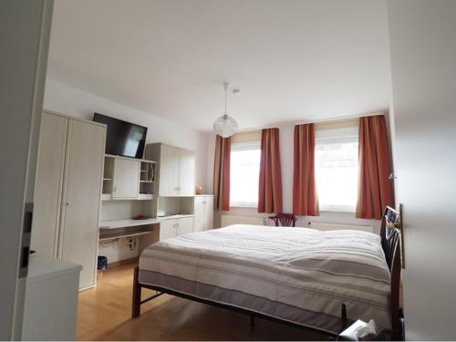 a bedroom with a bed and two windows with red curtains at Ferienwohnung Koppelblick in Plattenburg